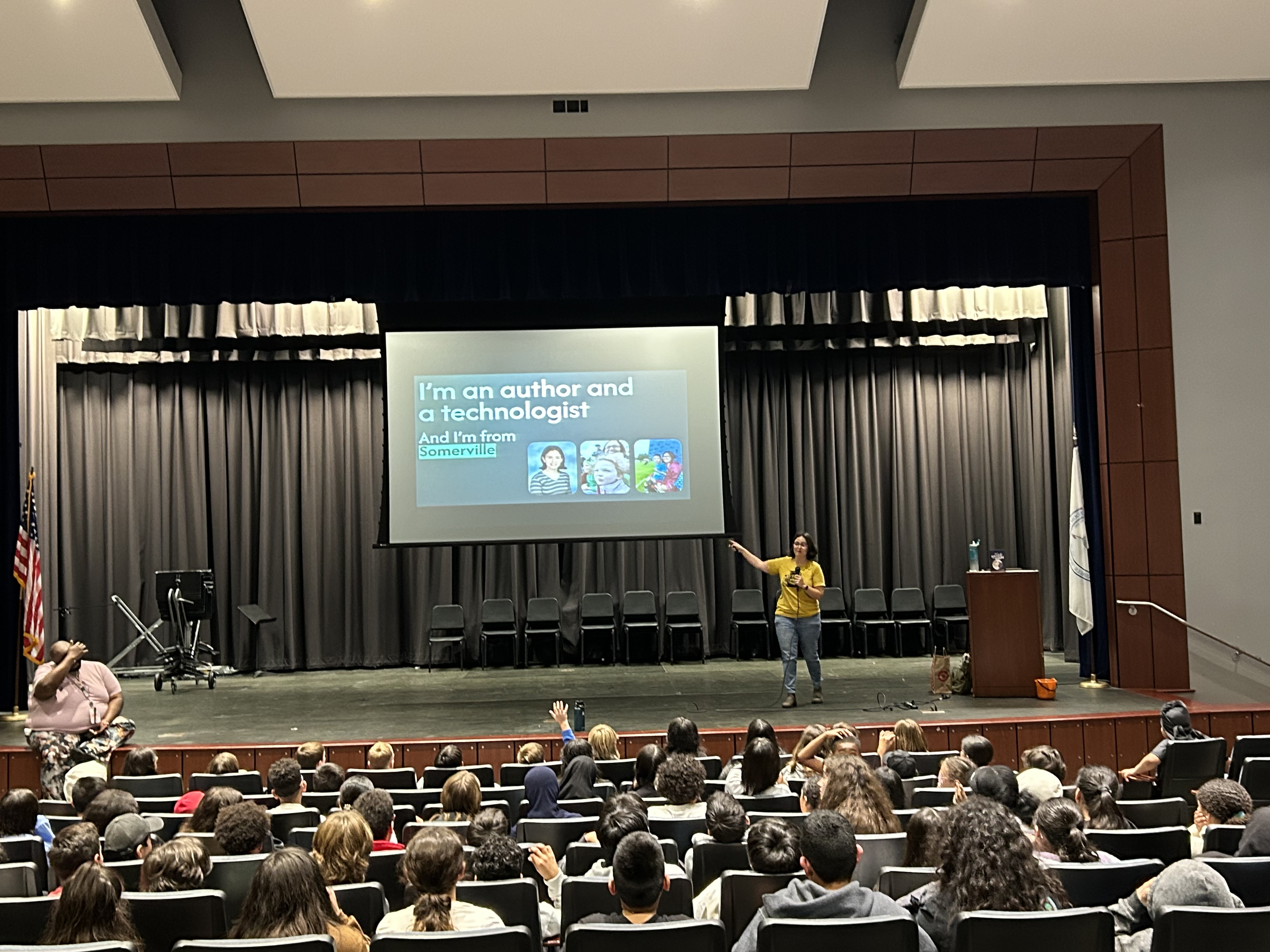 R. A. Dines presenting on stage to seated students